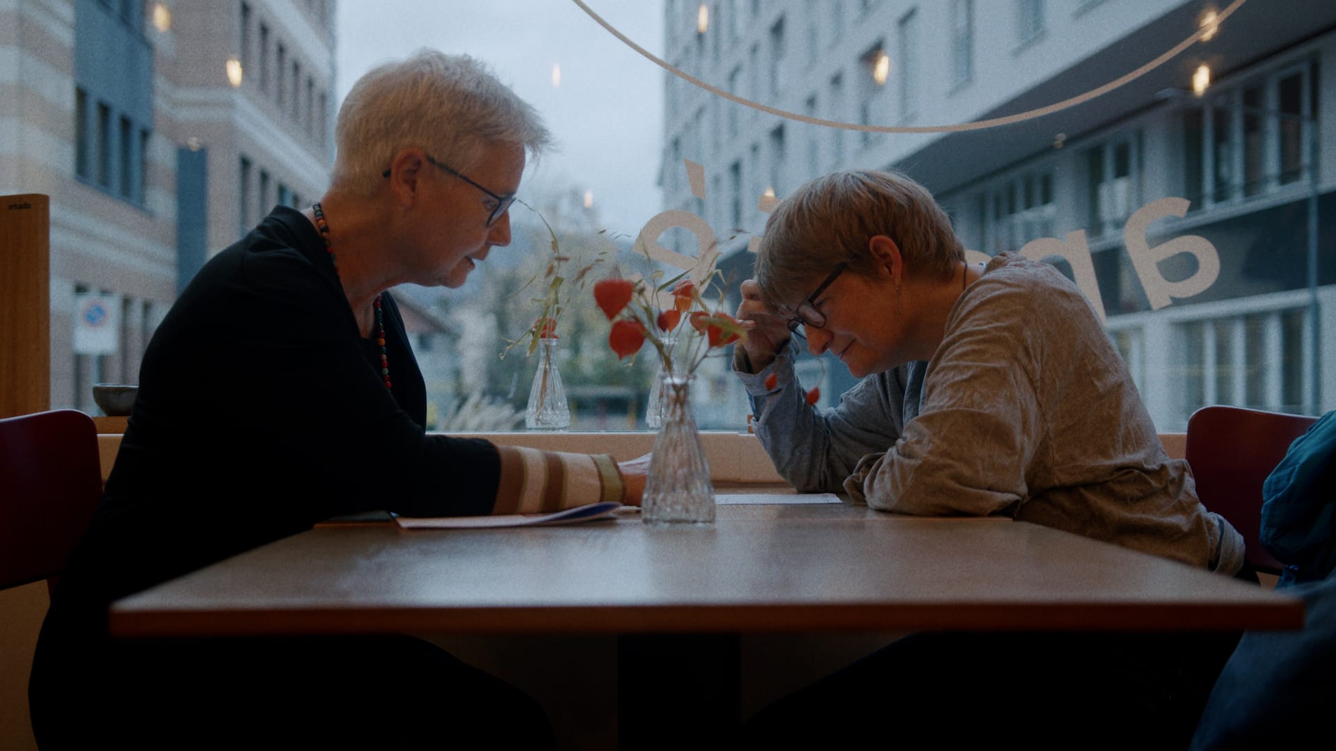 Zwei Personen sitzen sich im Gespräch an einem Cafétisch gegenüber.